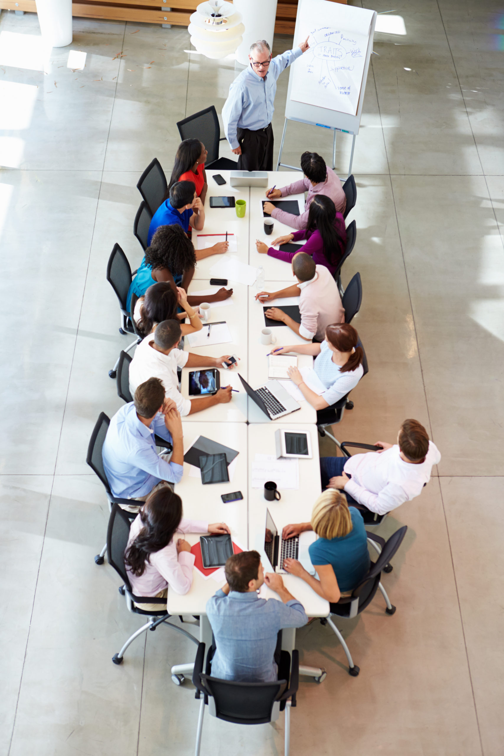 Businessman Addressing Meeting Around Boardroom Table